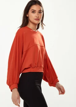 Women's Cropped Sweatshirt in Dark Orange with Voluminous Bat and Balloon Sleeves, Elastic Cuffs, and a Chic Design.